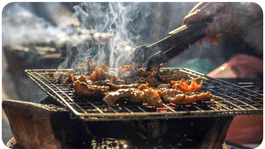 a person grilling food on a grill with smoke coming out of it