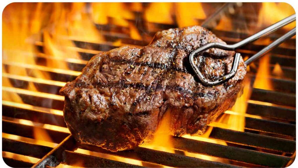 a steak being cooked on a grill with tongs